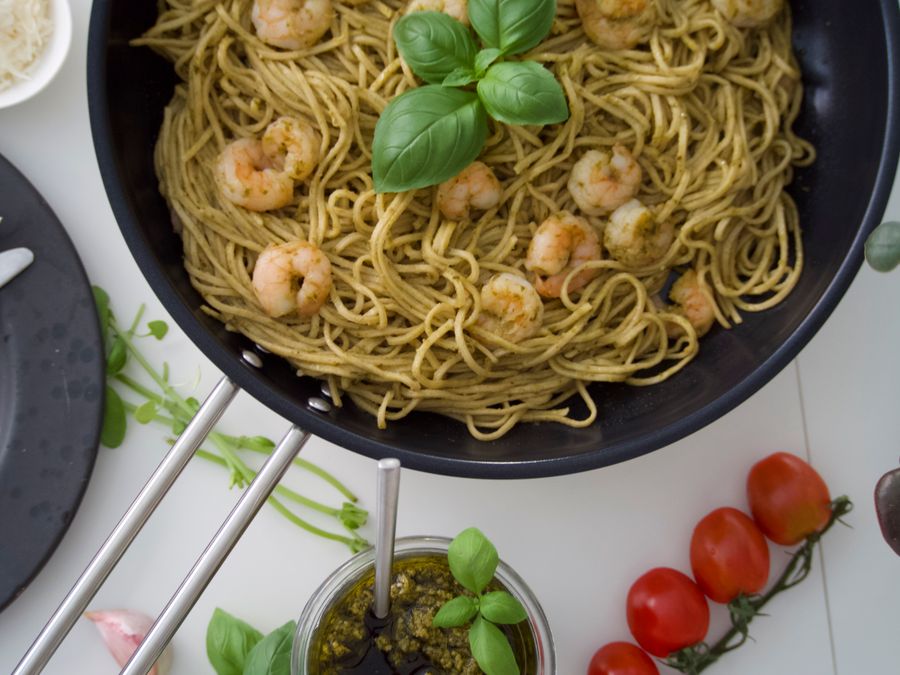 A pan of pesto spaghetti with prawns and fresh basil